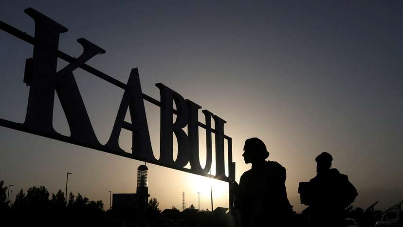 FILE PHOTO: Taliban soldiers stand in front of a sign at the international airport in Kabul