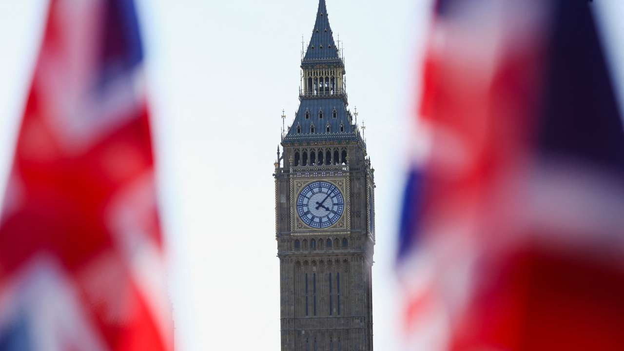 Union Jack flags flutter in the wind near Big Ben at Parliament Square in London