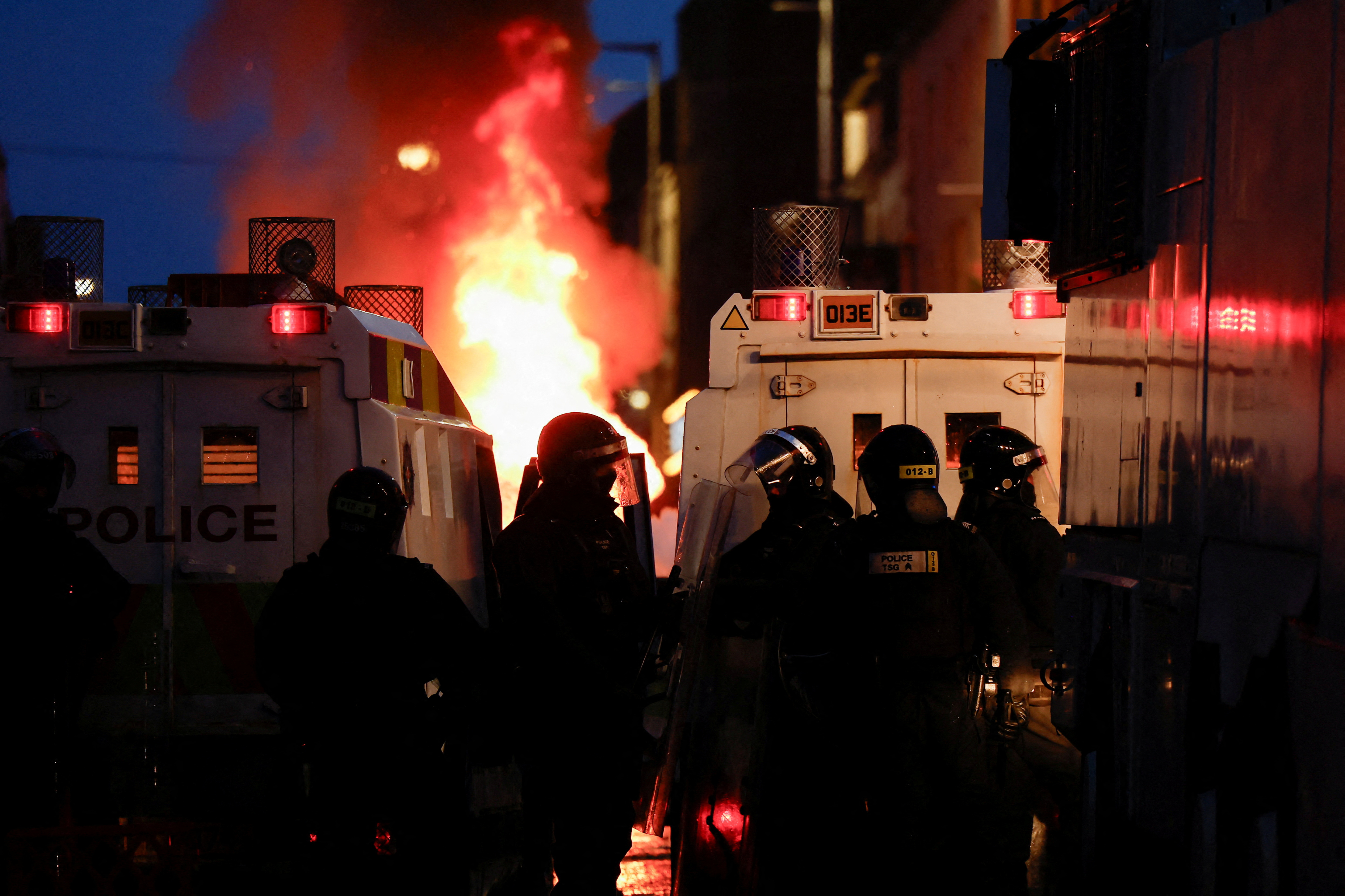 FILE PHOTO: Armed police in riot gear stand guard during a second night of riots, in Ballymena