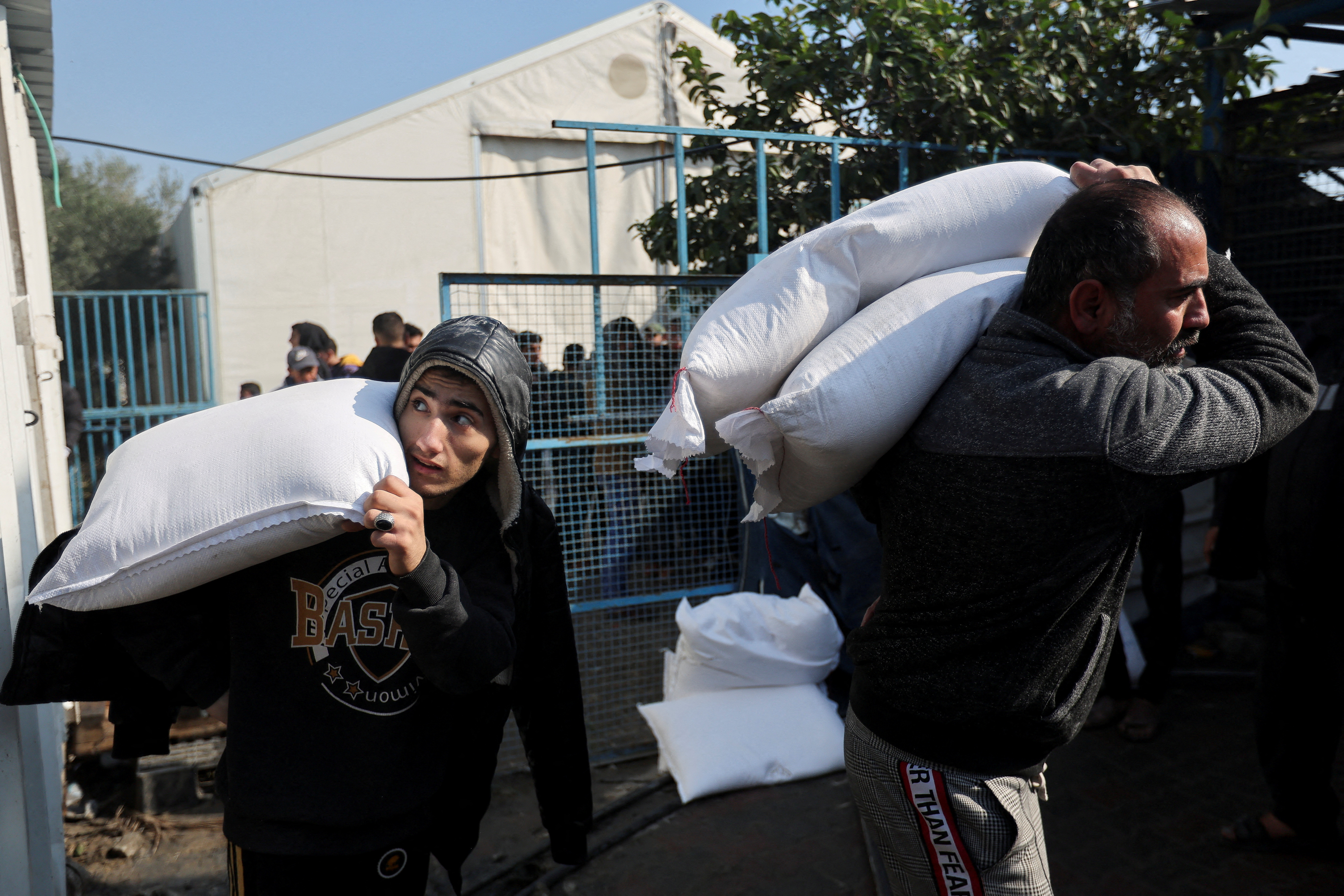 FILE PHOTO: Palestinians receive flour bags distributed by UNRWA during a temporary truce between Hamas and Israel, in Khan Younis