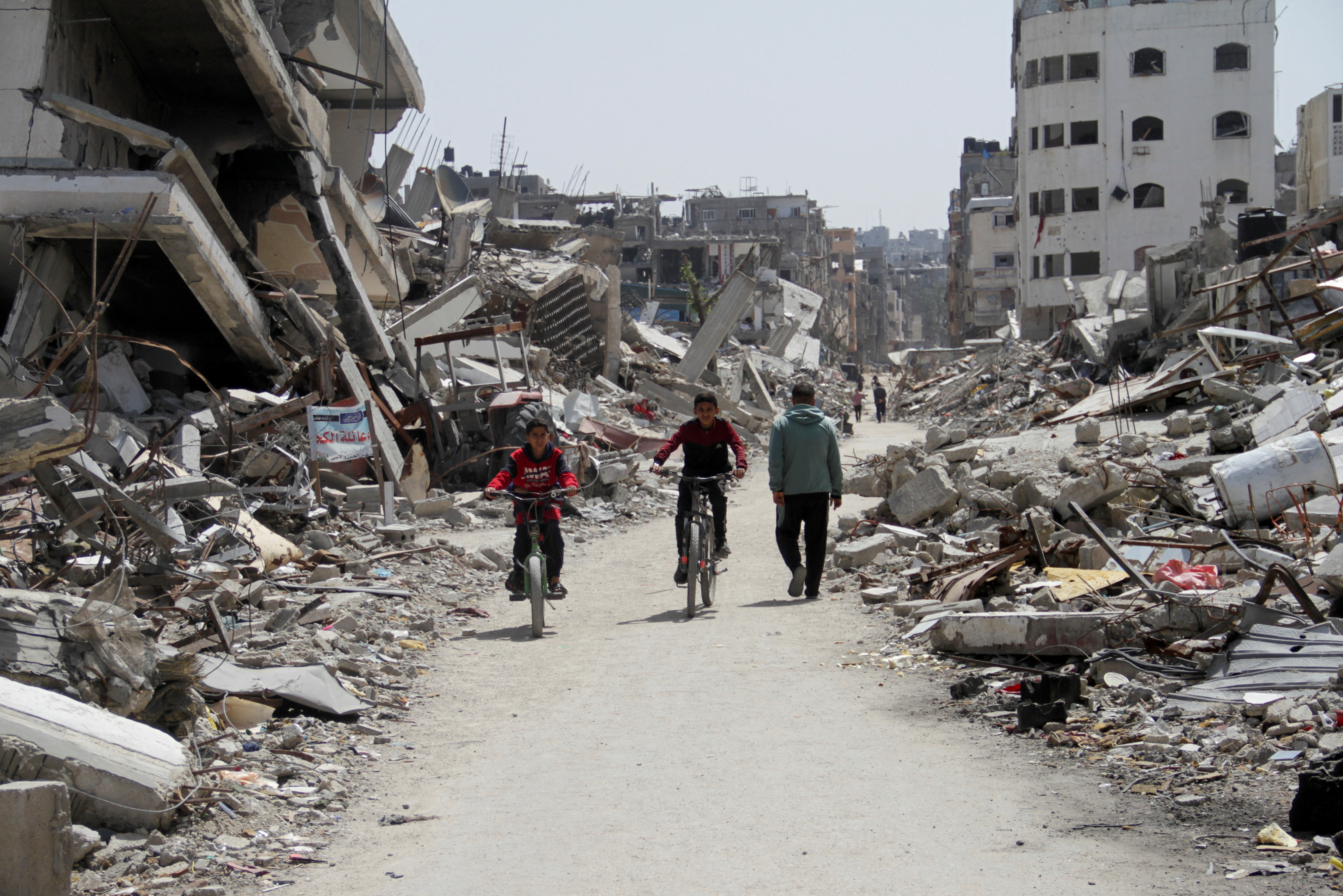 Palestinians ride bicycles past the ruins of houses and buildings destroyed during Israel’ military offensive, in the northern Gaza Strip