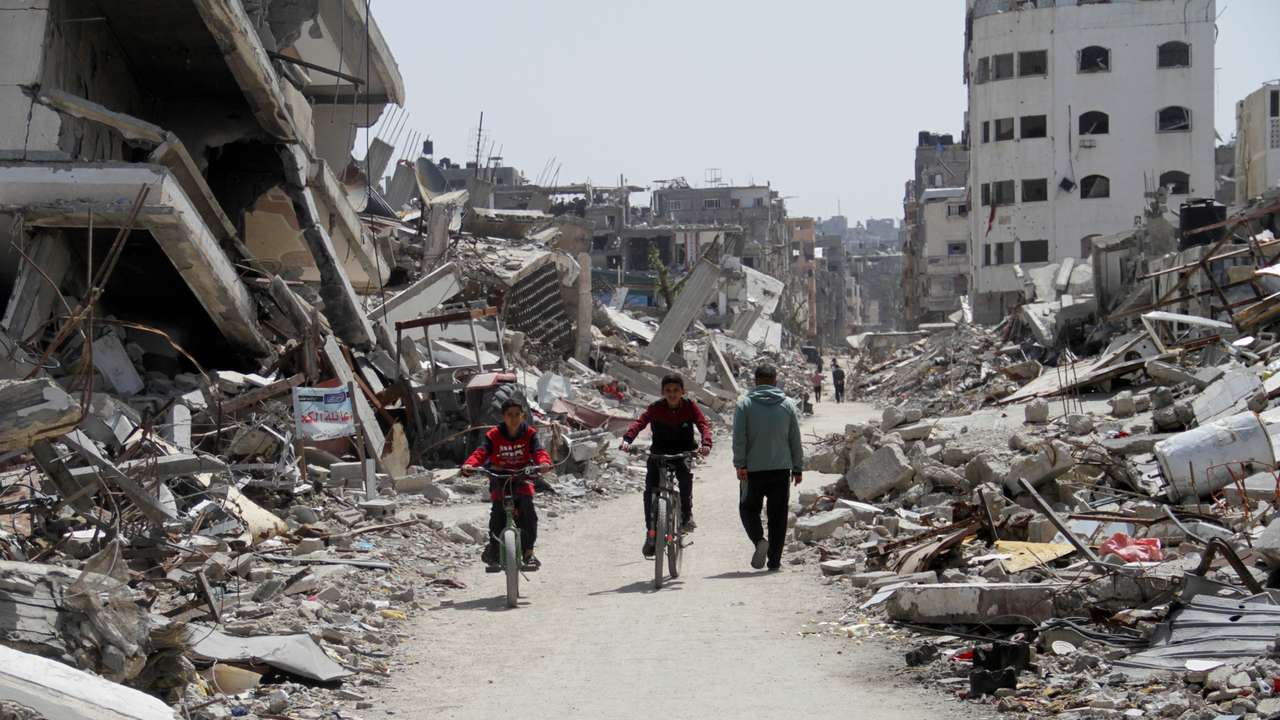 Palestinians ride bicycles past the ruins of houses and buildings destroyed during Israel’ military offensive, in the northern Gaza Strip