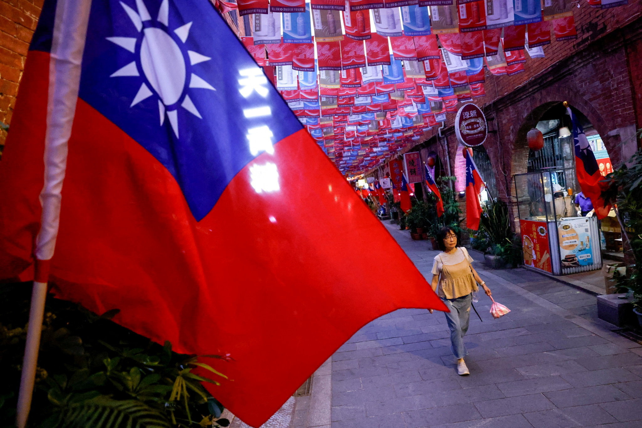 A woman walks past a street lined with Taiwanese flags, in Kinmen