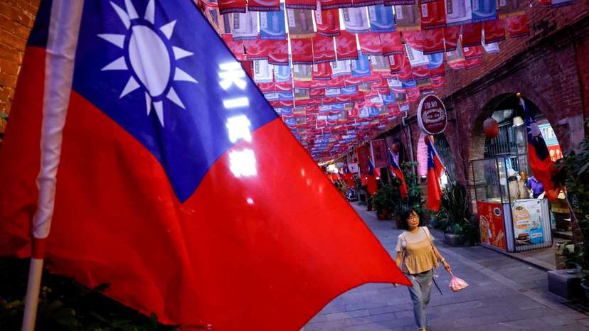 A woman walks past a street lined with Taiwanese flags, in Kinmen