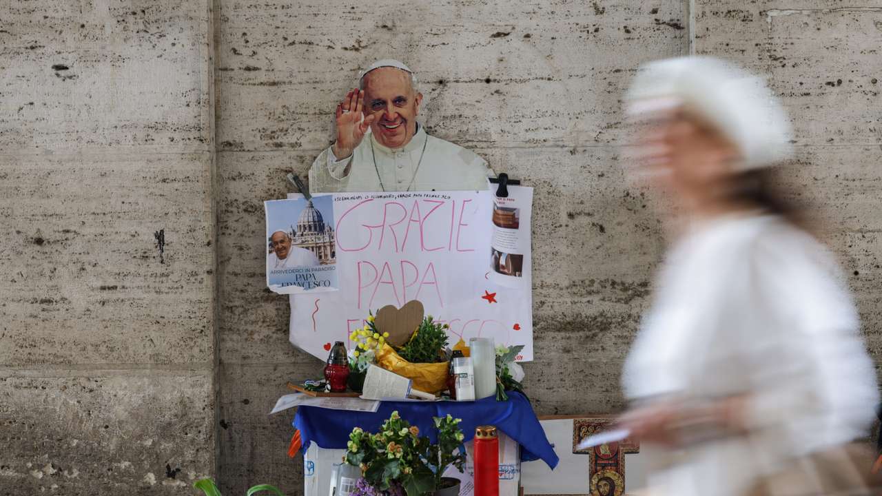 A person walks past an images of late Pope Francis, in Rome