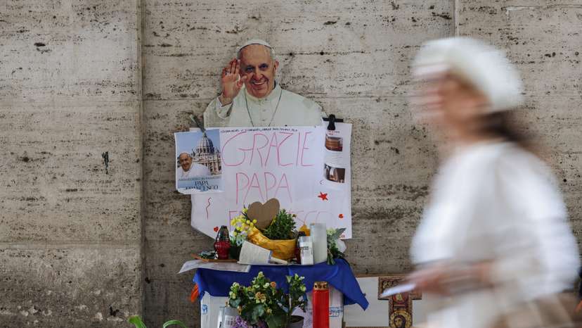 A person walks past an images of late Pope Francis, in Rome