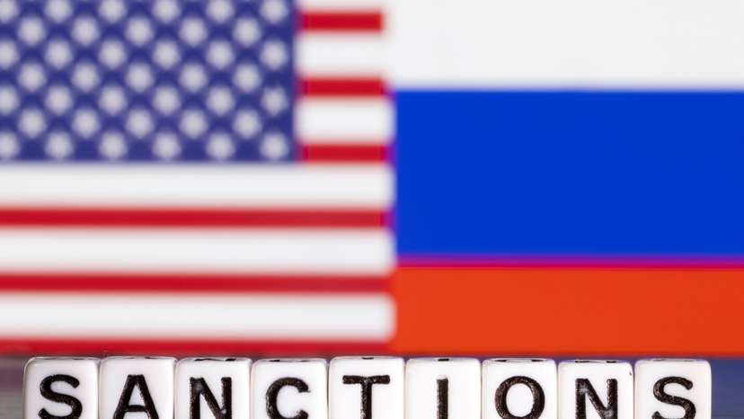 Illustration shows letters arranged to read "Sanctions" in front of flag colors of U.S. and Russia
