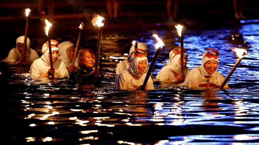 "Ama" female free divers, who harvest sea life from the ocean, lead volunteers as they swim with torches during Shirahama Ama matsuri in Minamiboso