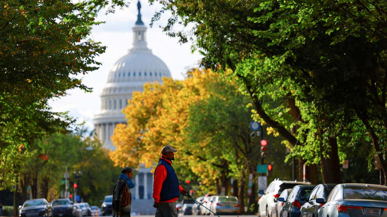 A couple walks with a dog near the U.S. Capitol building, in Washington