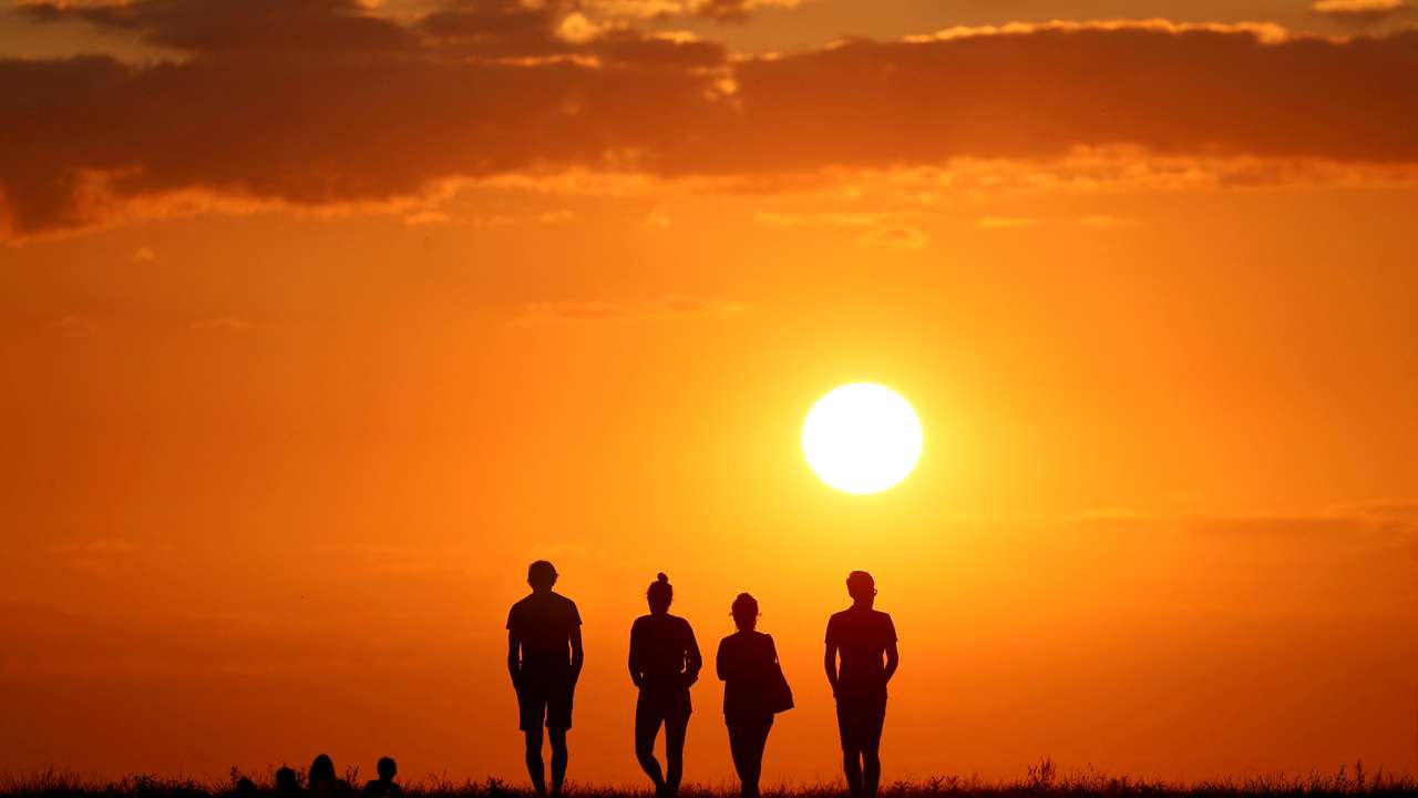 FILE PHOTO: People are silhouetted against the setting sun on top of the Drachenberg in Berlin