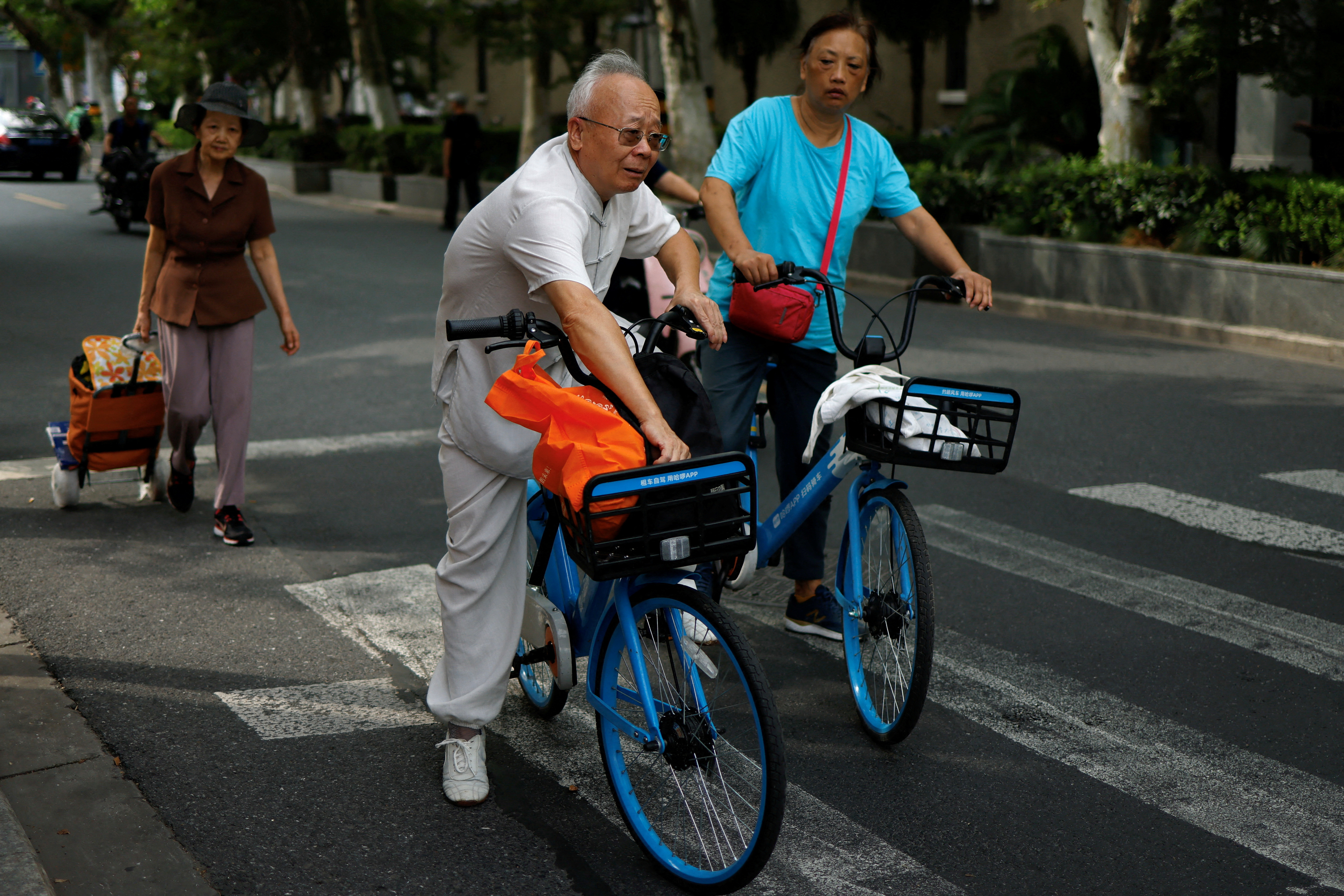 FILE PHOTO: Elderly people ride bikes from a bike-sharing service on a street in Shanghai