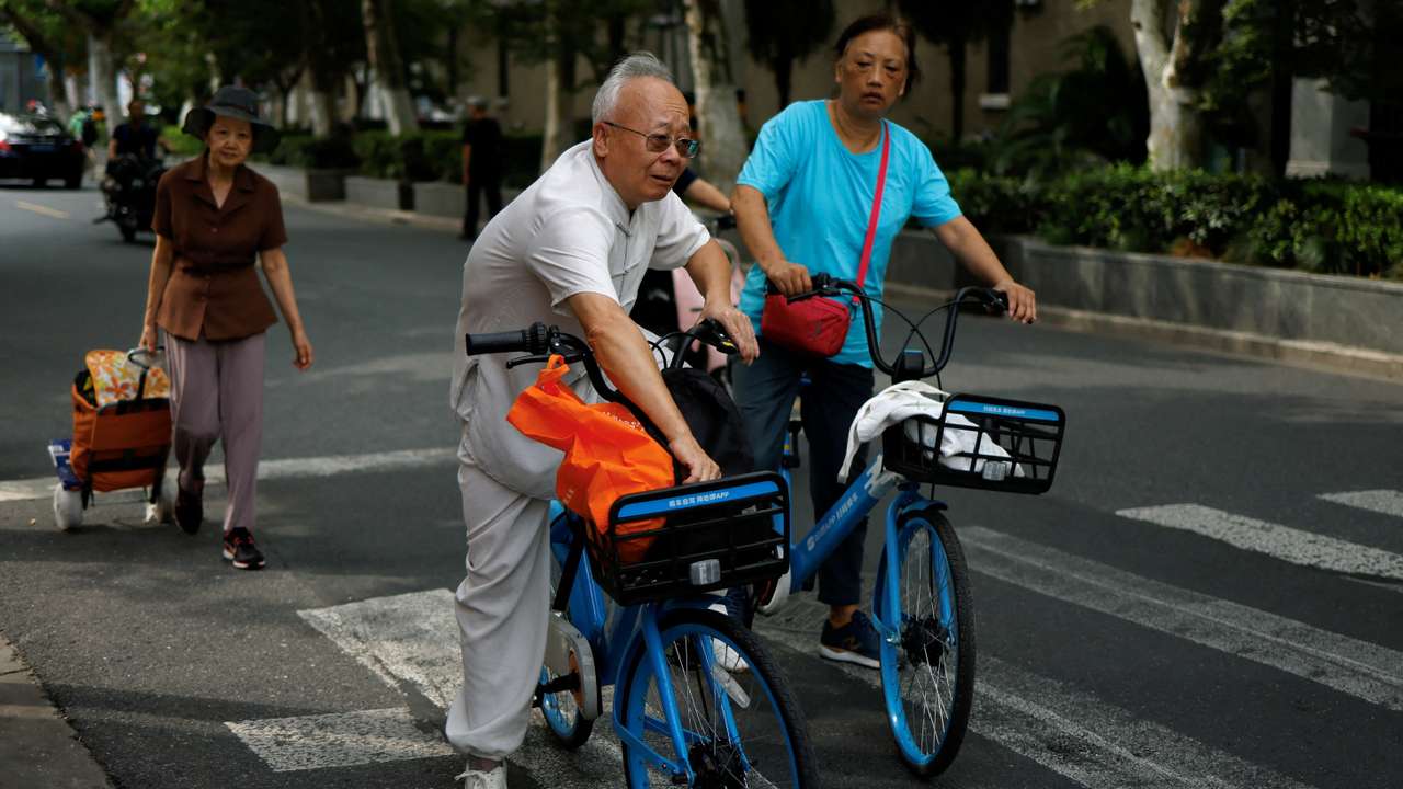 FILE PHOTO: Elderly people ride bikes from a bike-sharing service on a street in Shanghai
