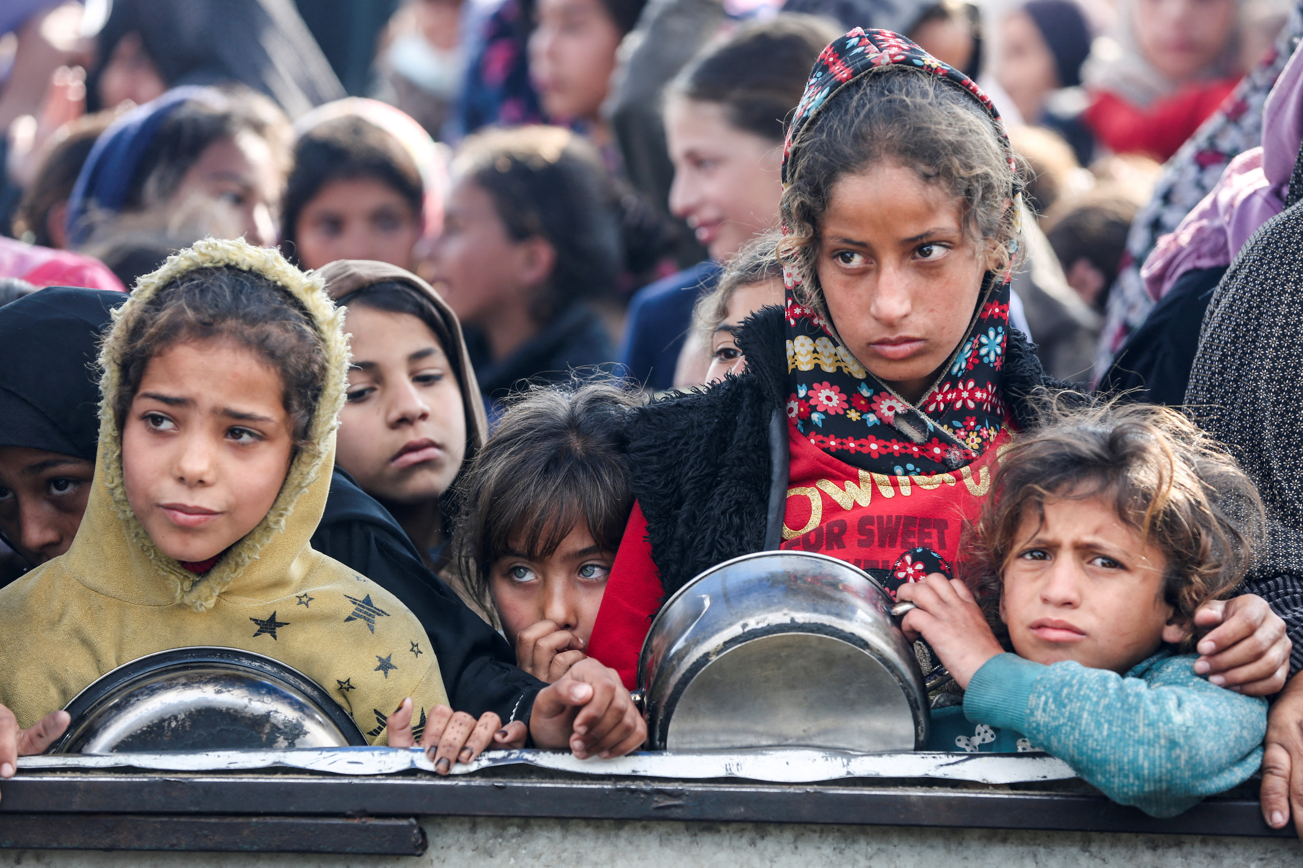 Palestinians gather to receive food cooked by a charity kitchen, in Khan Younis