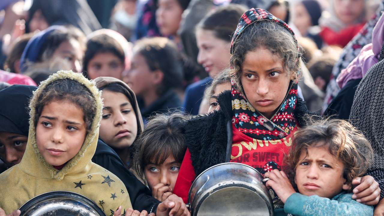 Palestinians gather to receive food cooked by a charity kitchen, in Khan Younis