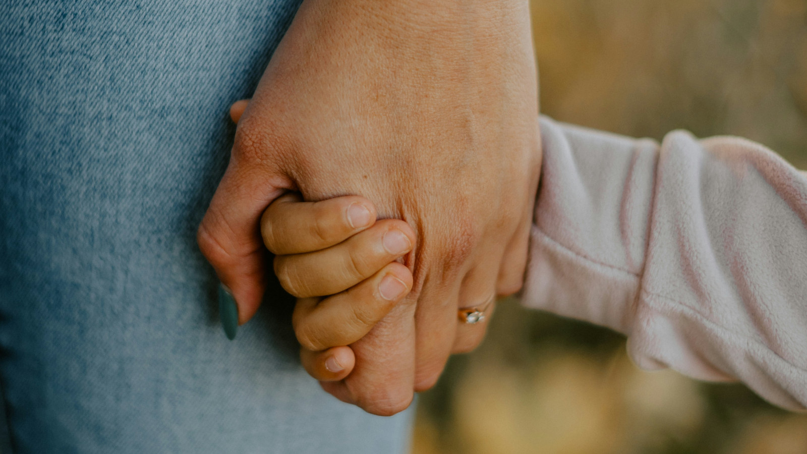 M&atilde;e segura a m&atilde;o de crian&ccedil;a.