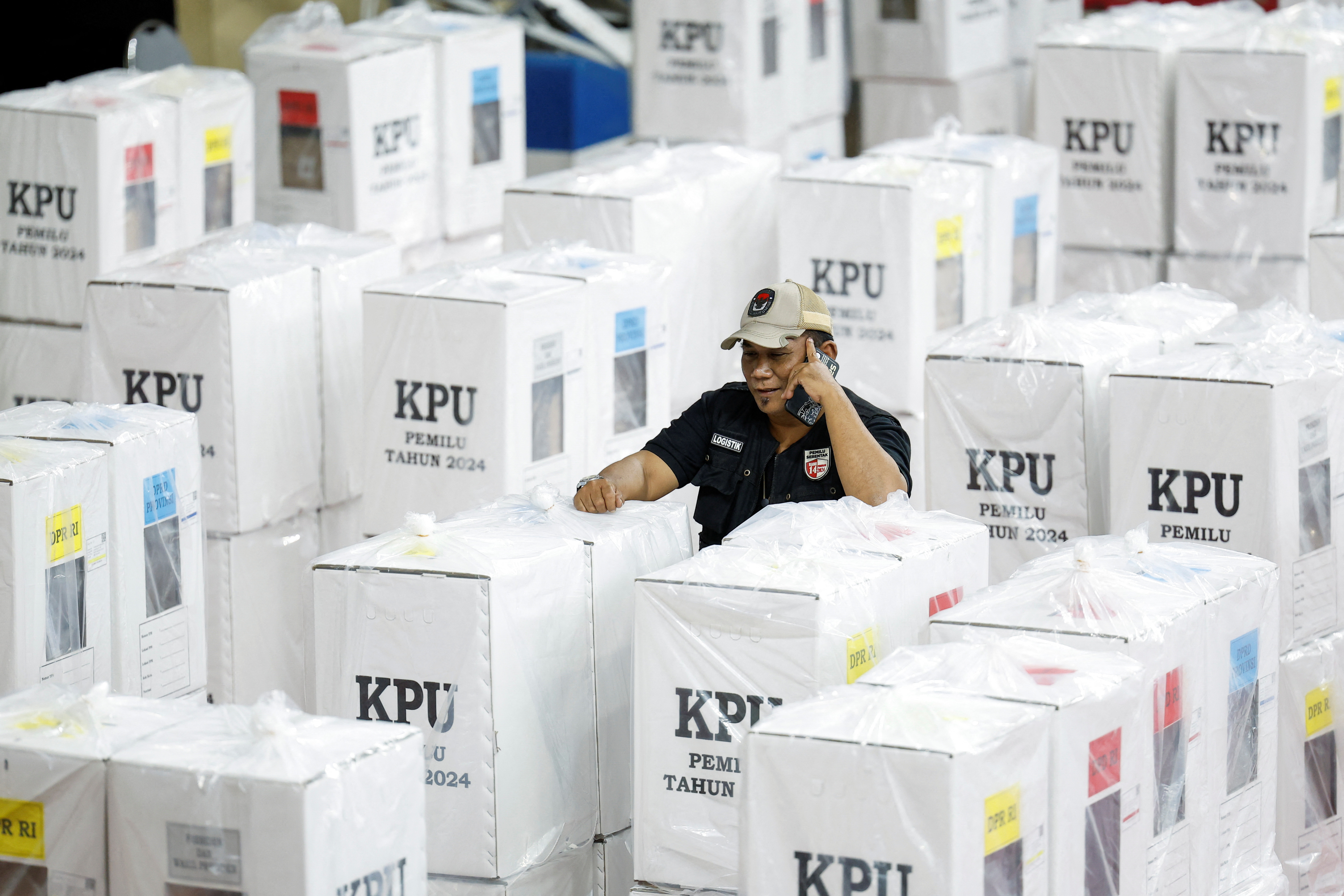 An election commission officer speaks on a phone, as he stands among ballot boxes ahead of general election in Jakarta