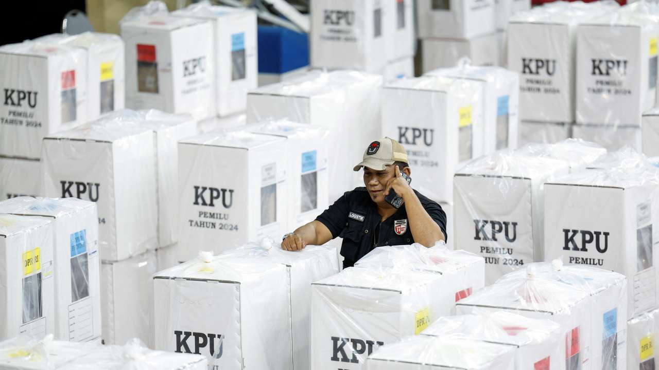 An election commission officer speaks on a phone, as he stands among ballot boxes ahead of general election in Jakarta
