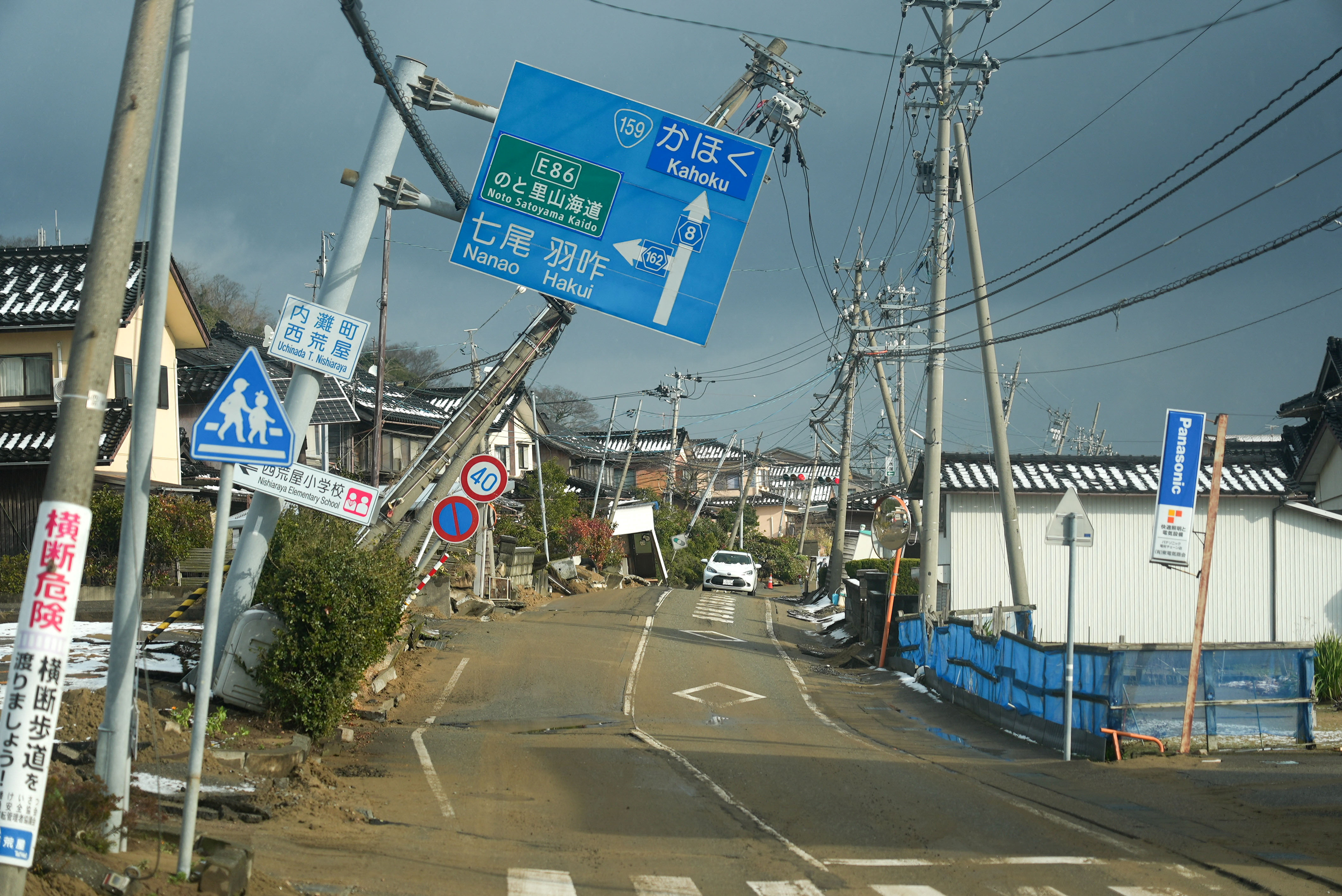 Road signs are tilted over a road damaged by the January 1 earthquake in Nishiaraya
