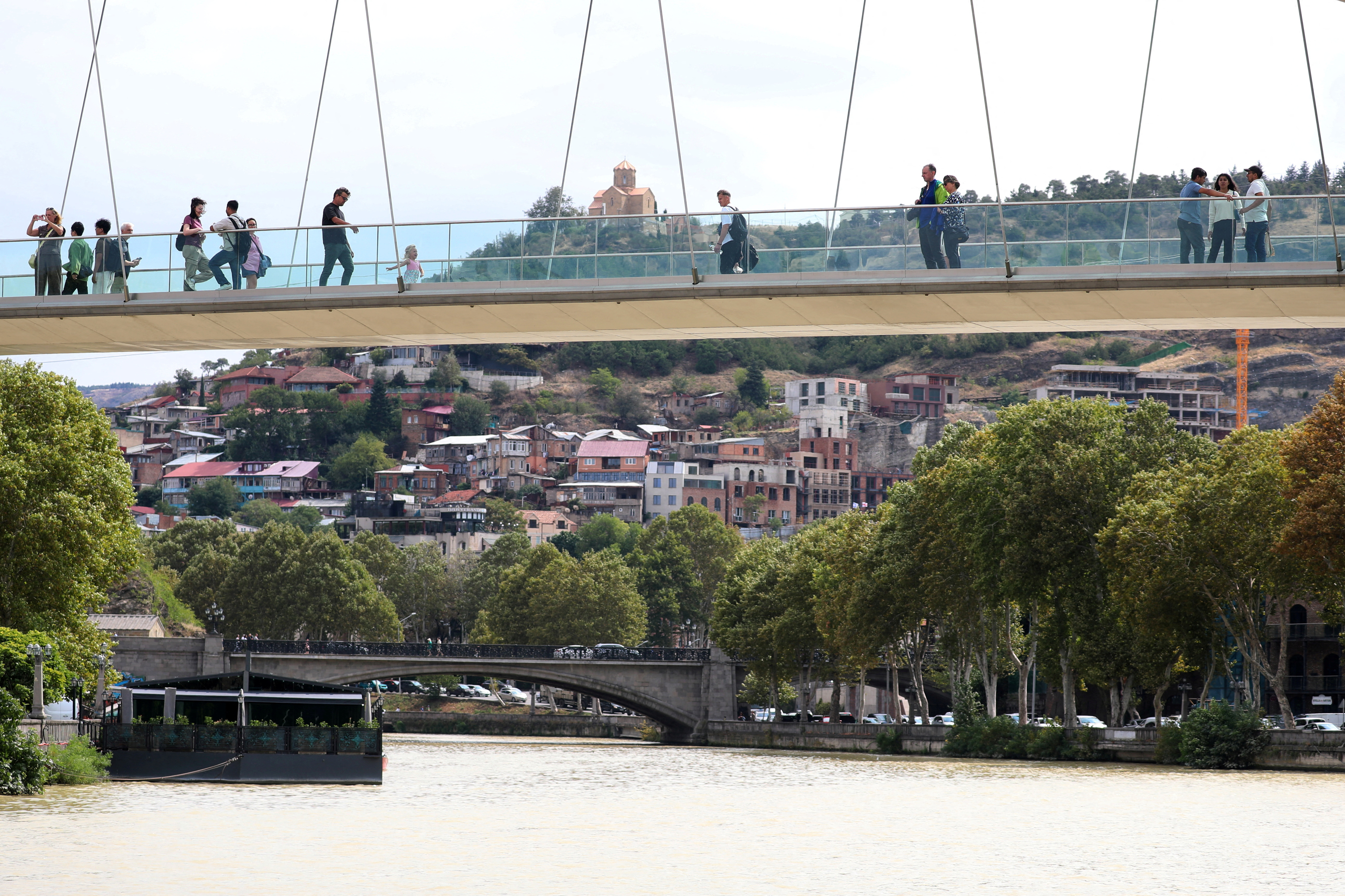 FILE PHOTO: People walk across the Bridge of Peace over the Mtkvari river in Tbilisi