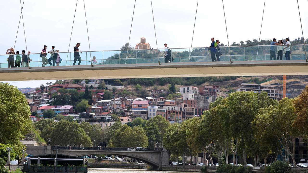FILE PHOTO: People walk across the Bridge of Peace over the Mtkvari river in Tbilisi