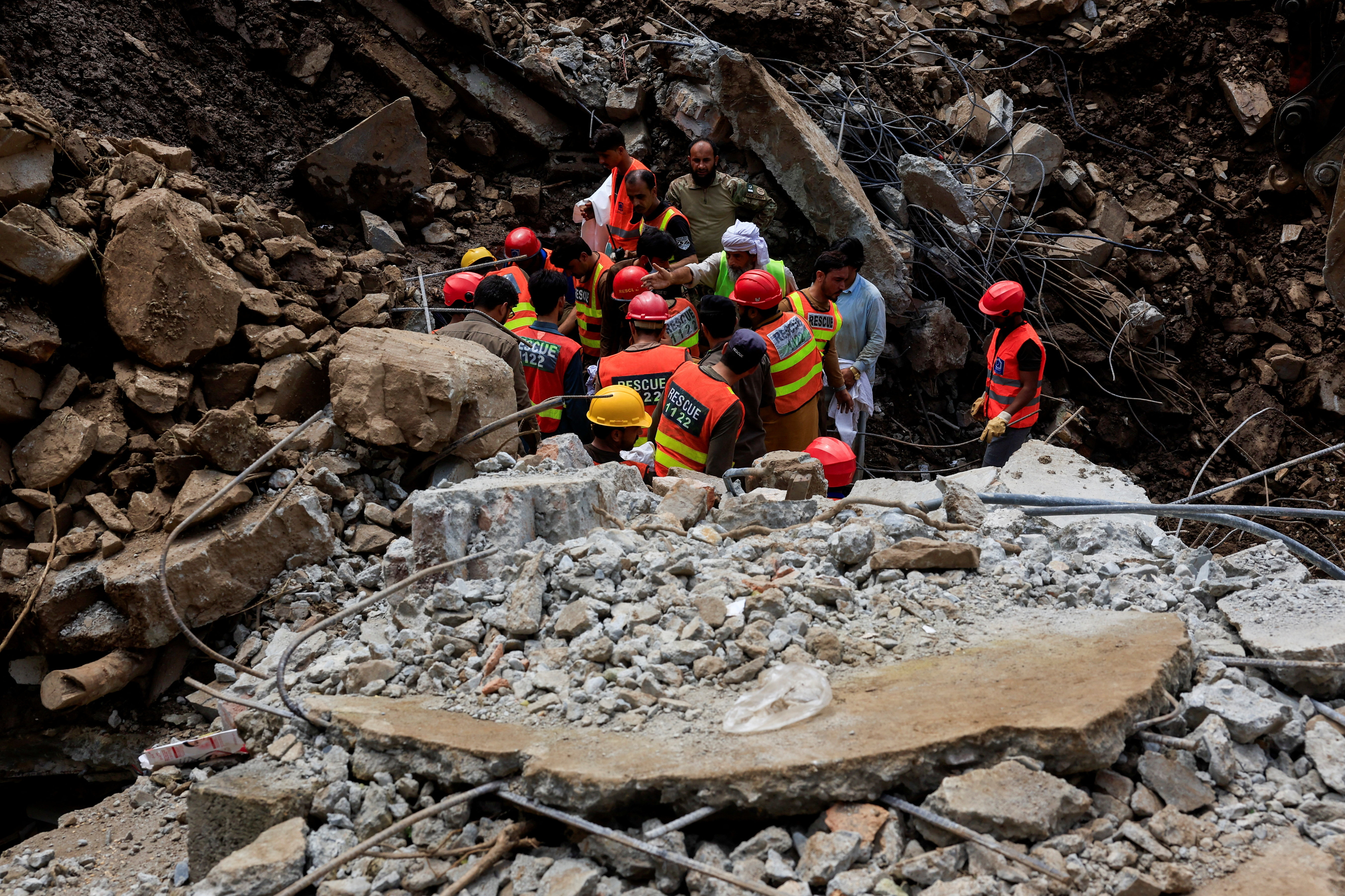 Rescue workers look for victims, following a storm that caused heavy rains and flooding in Dalori Bala village