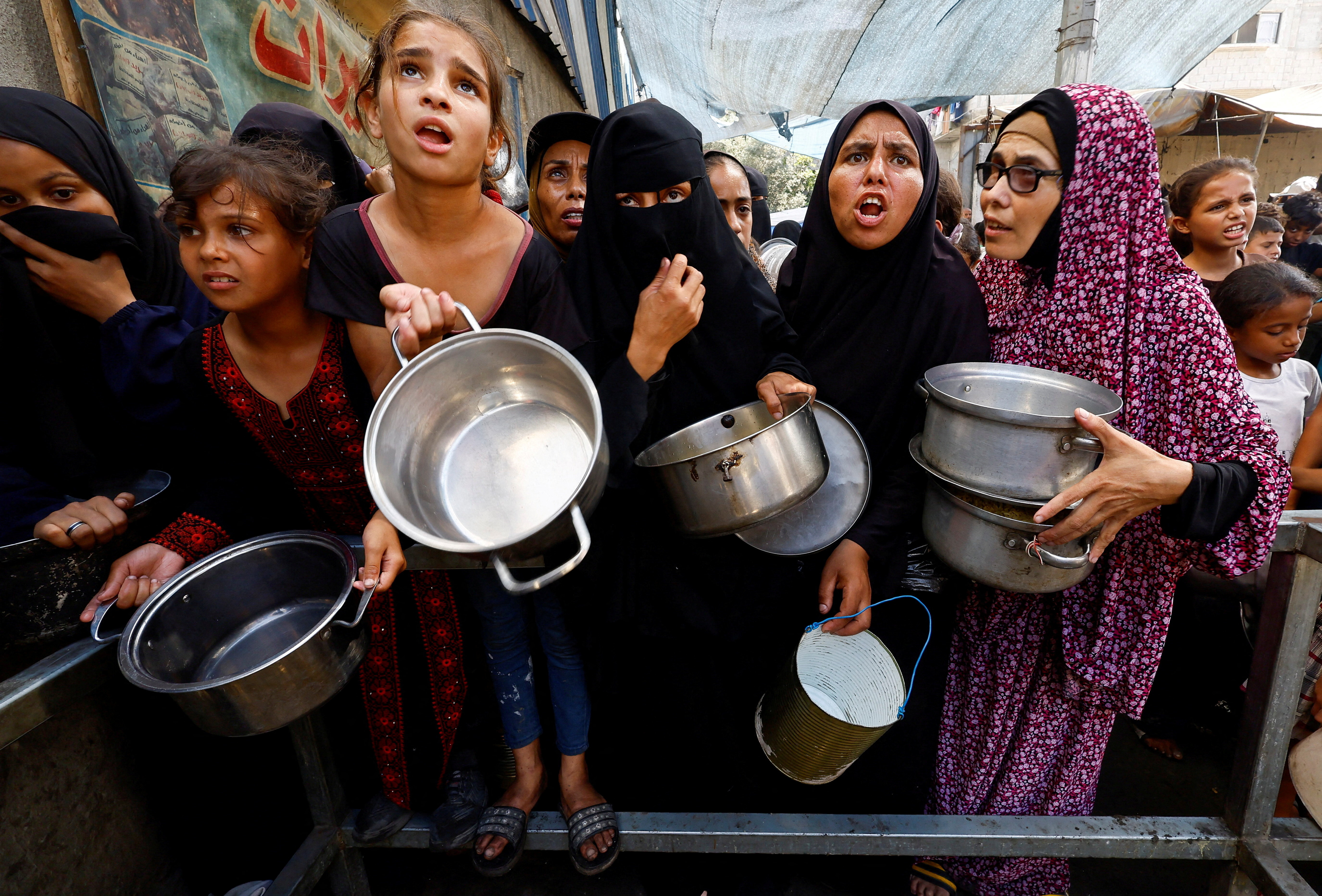 Palestinians gather to receive food from a charity kitchen, in Nuseirat