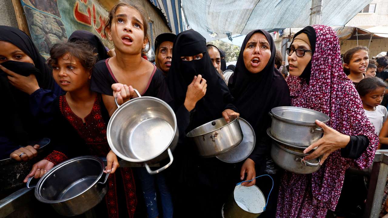 Palestinians gather to receive food from a charity kitchen, in Nuseirat
