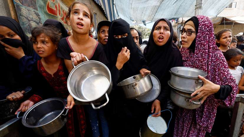 Palestinians gather to receive food from a charity kitchen, in Nuseirat