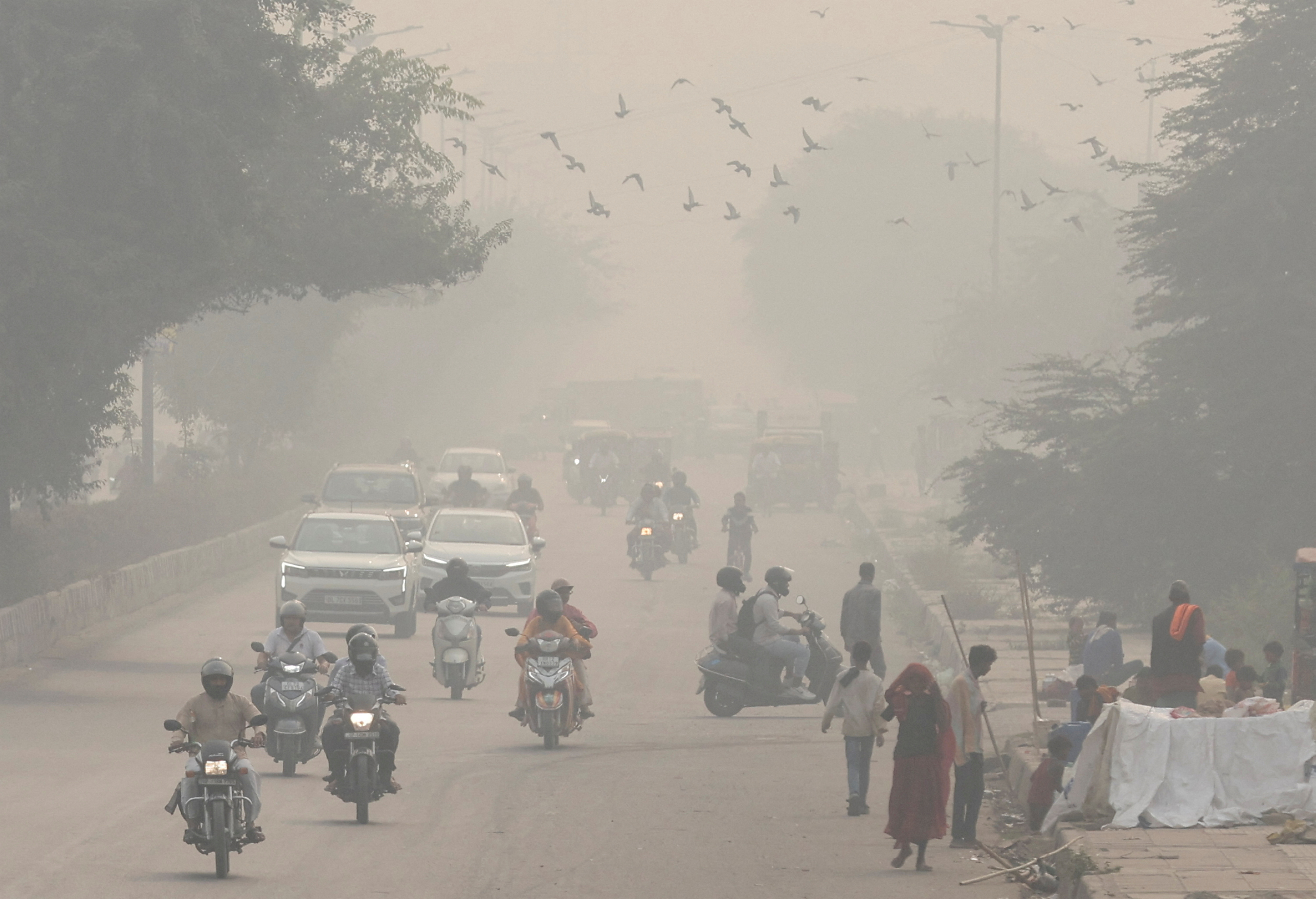 FILE PHOTO: People and vehicles are seen on a road amidst the morning smog in New Delhi
