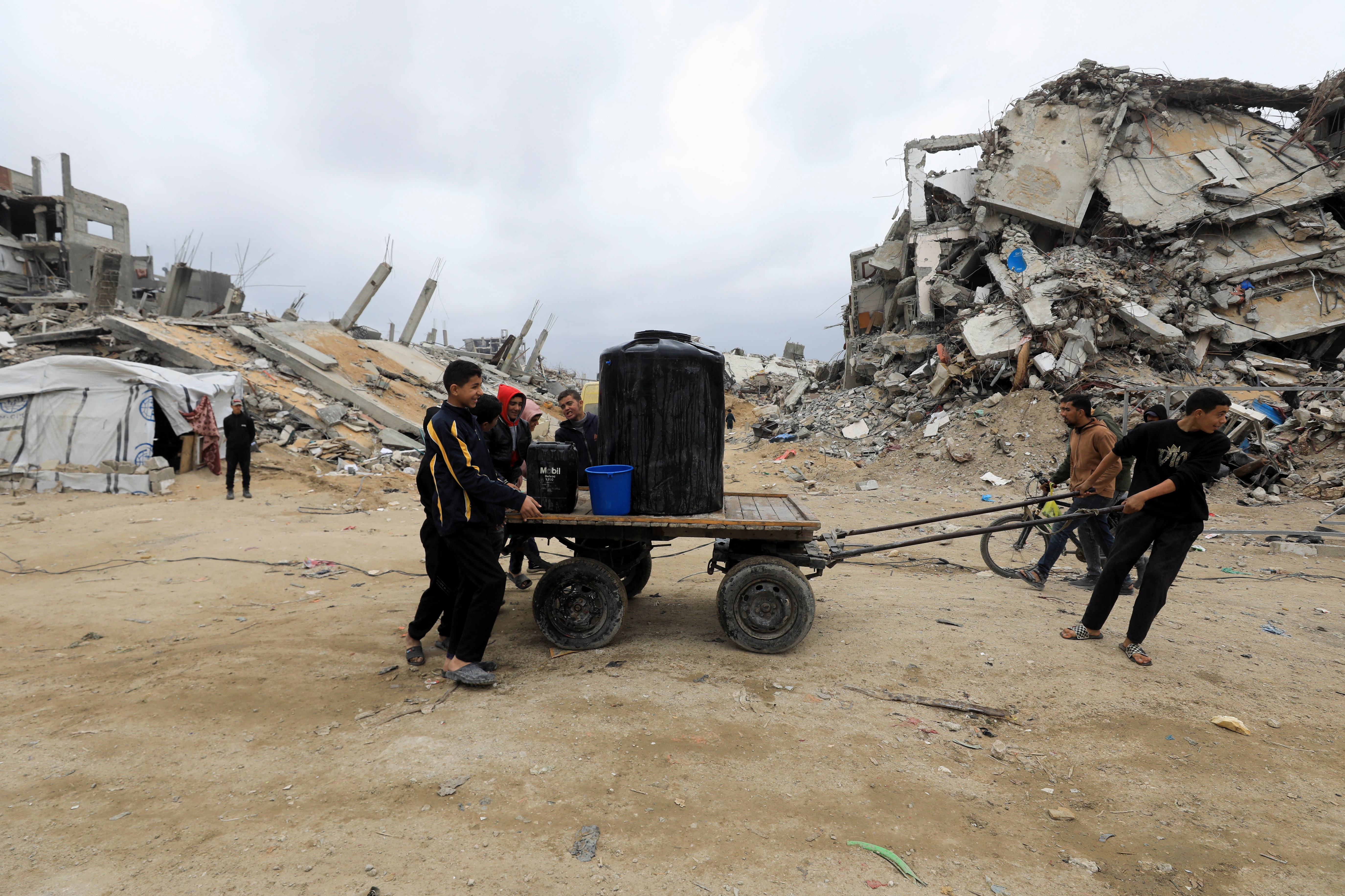 Palestinians push a cart with water tank in Jabalia refugee camp