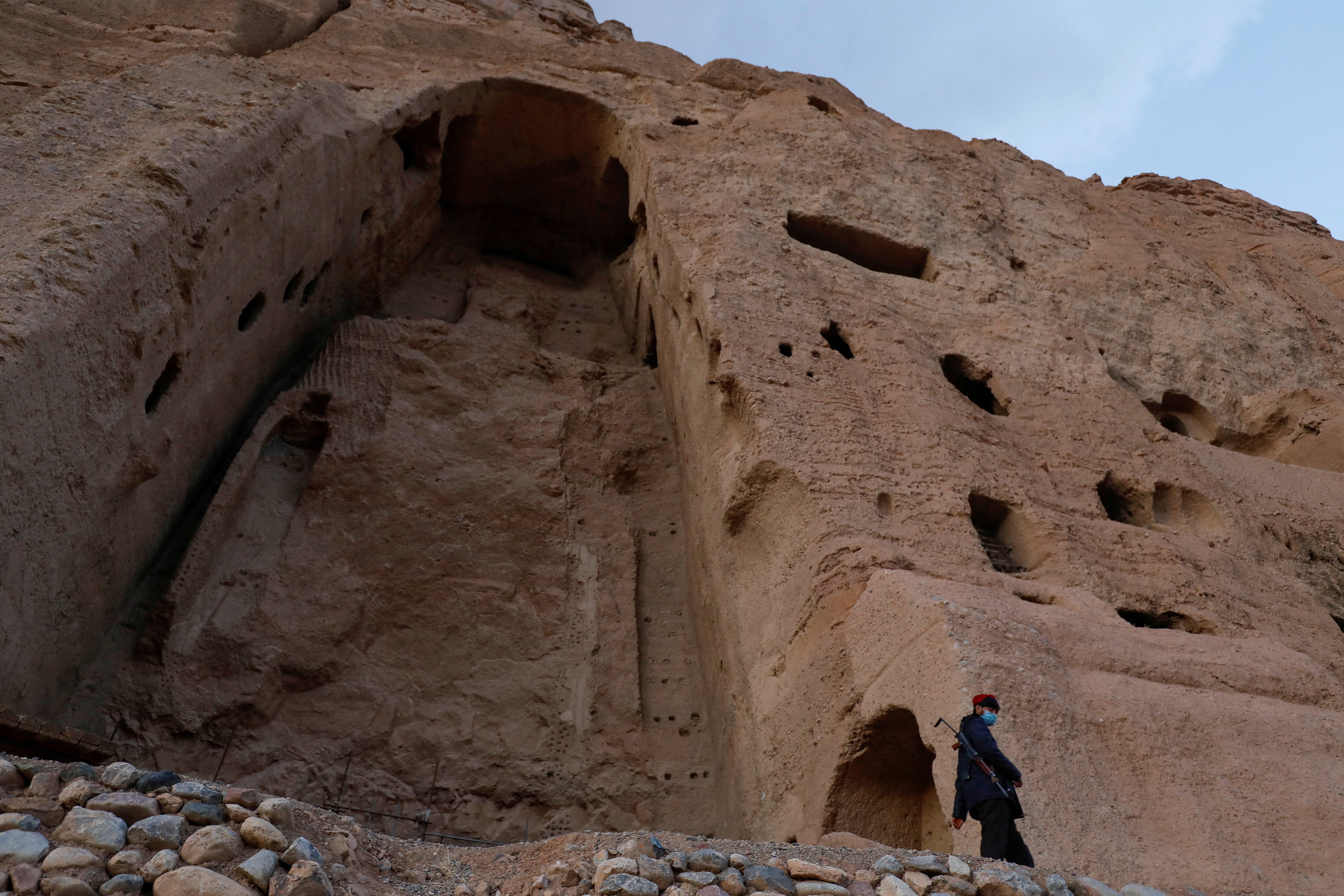 FILE PHOTO: A Taliban soldier stands guard in front of the ruins of a 1500-year-old Buddha statue in Bamyan