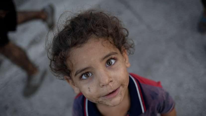 A displaced kid reacts to a camera outside his makeshift shelter at a roadside in Beirut