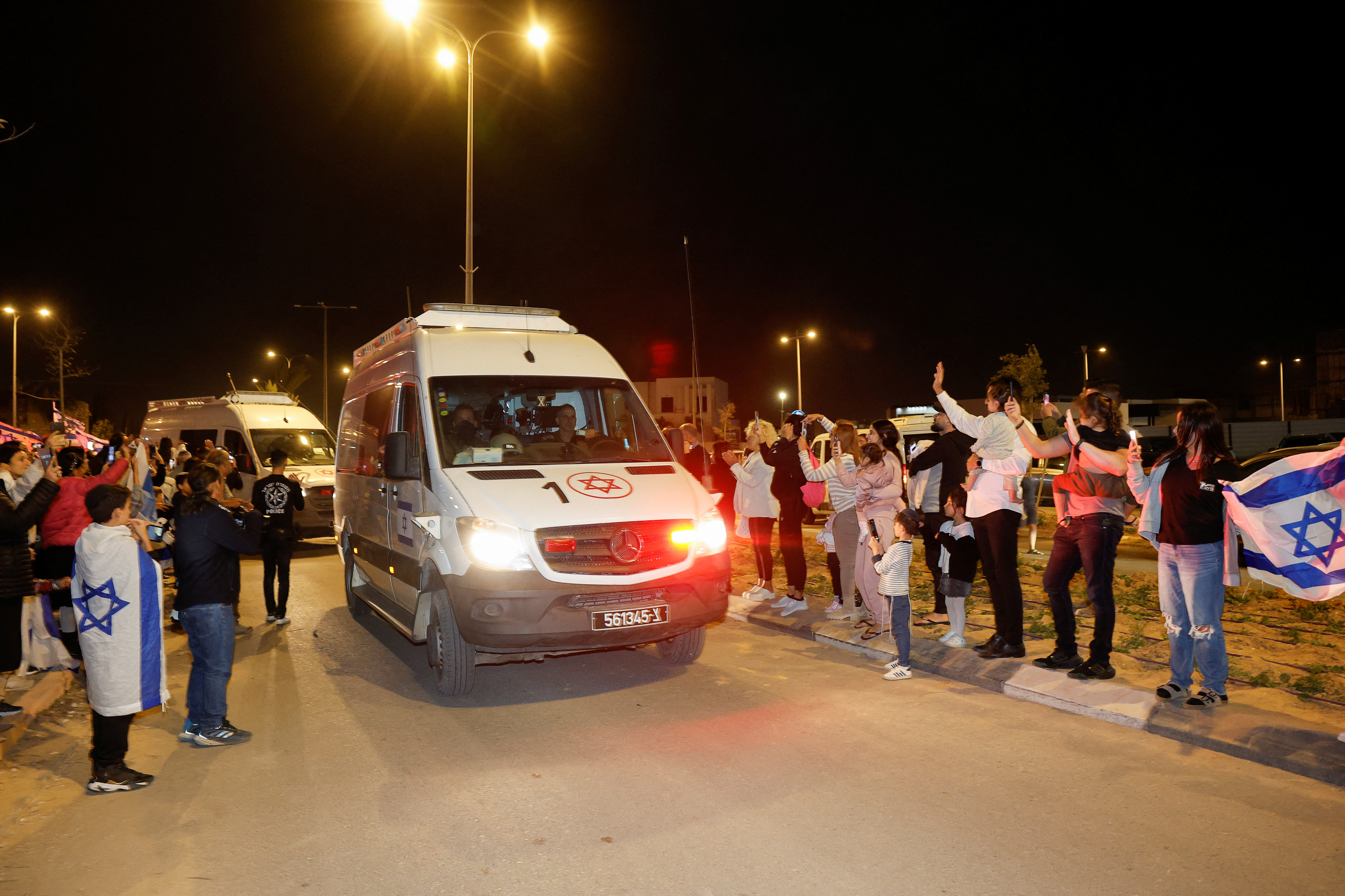 People react to the convoy carrying newly released hostages, in Ofakim