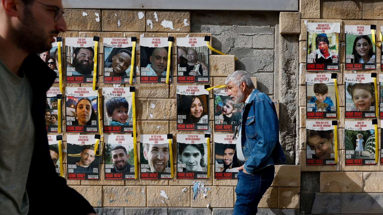 People walk past posters with photos of hostages, in Tel Aviv