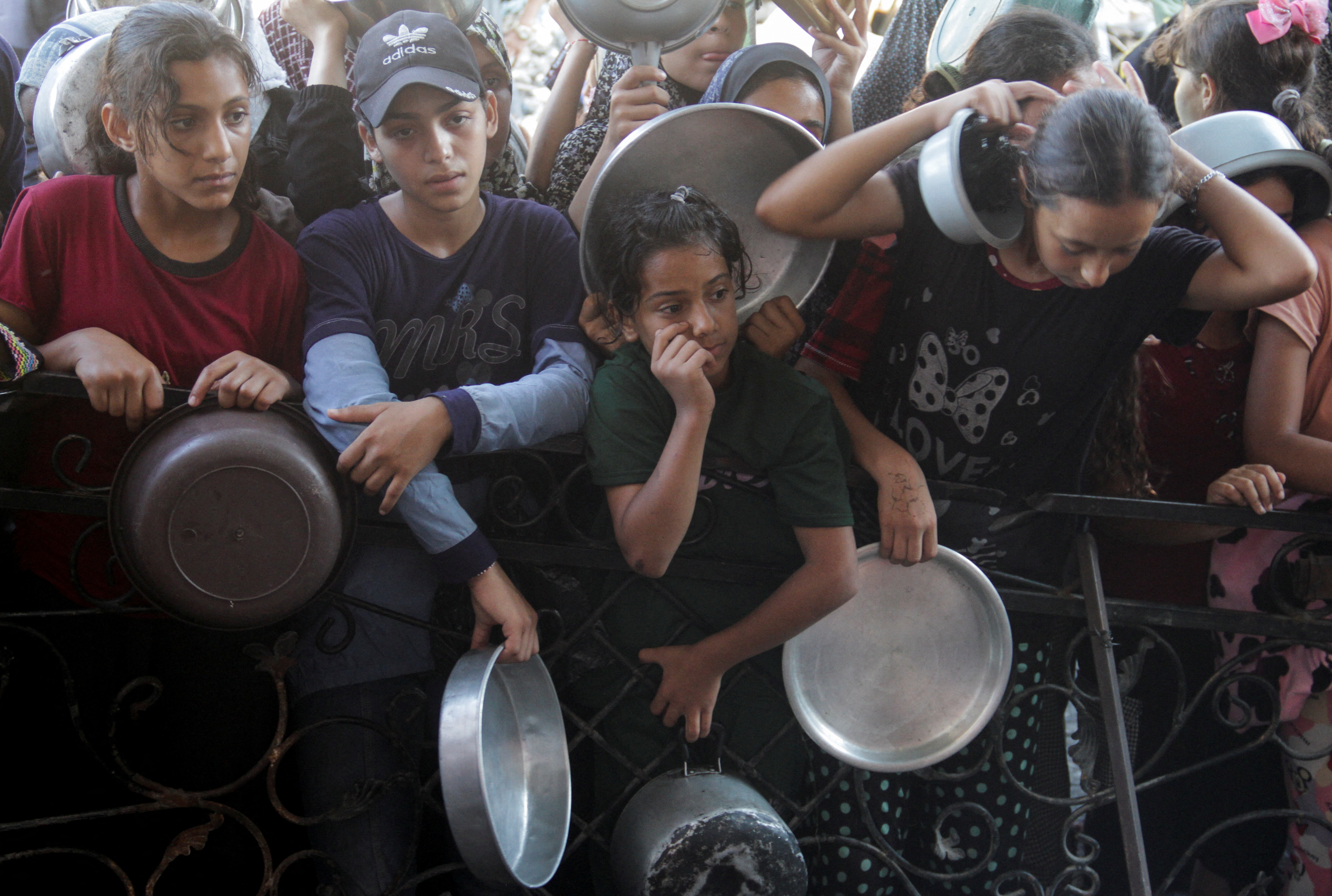 Palestinians wait to receive food cooked by a charity kitchen in the northern Gaza Strip