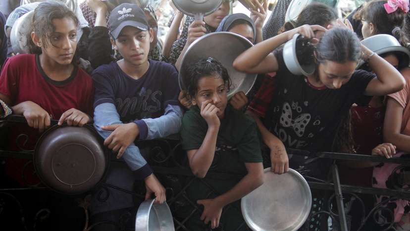 Palestinians wait to receive food cooked by a charity kitchen in the northern Gaza Strip