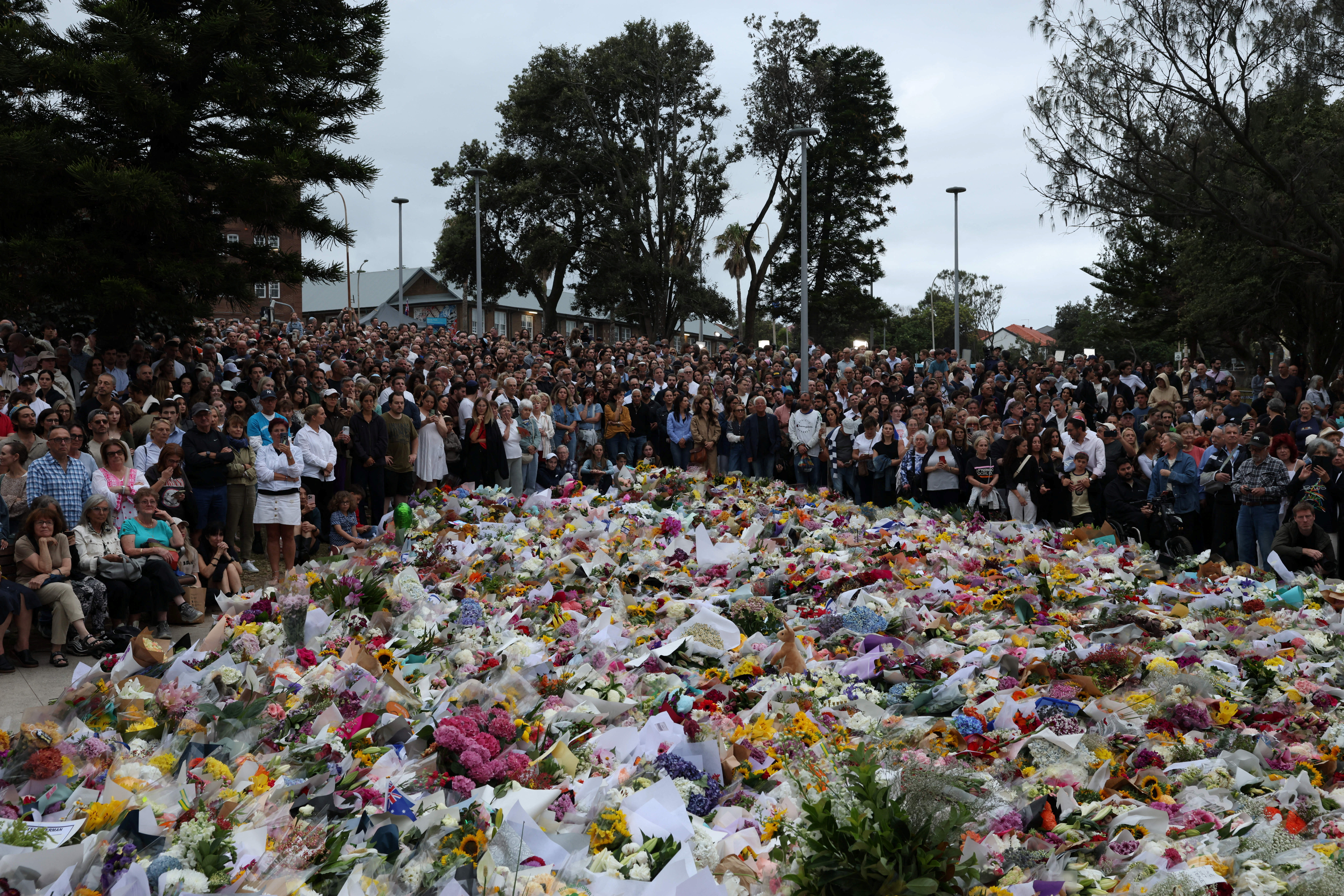 People lay flowers and pay tribute at Bondi Beach to honour the victims of a mass shooting that targeted a Jewish Holiday celebration on Sunday at Bondi Beach, in Sydney