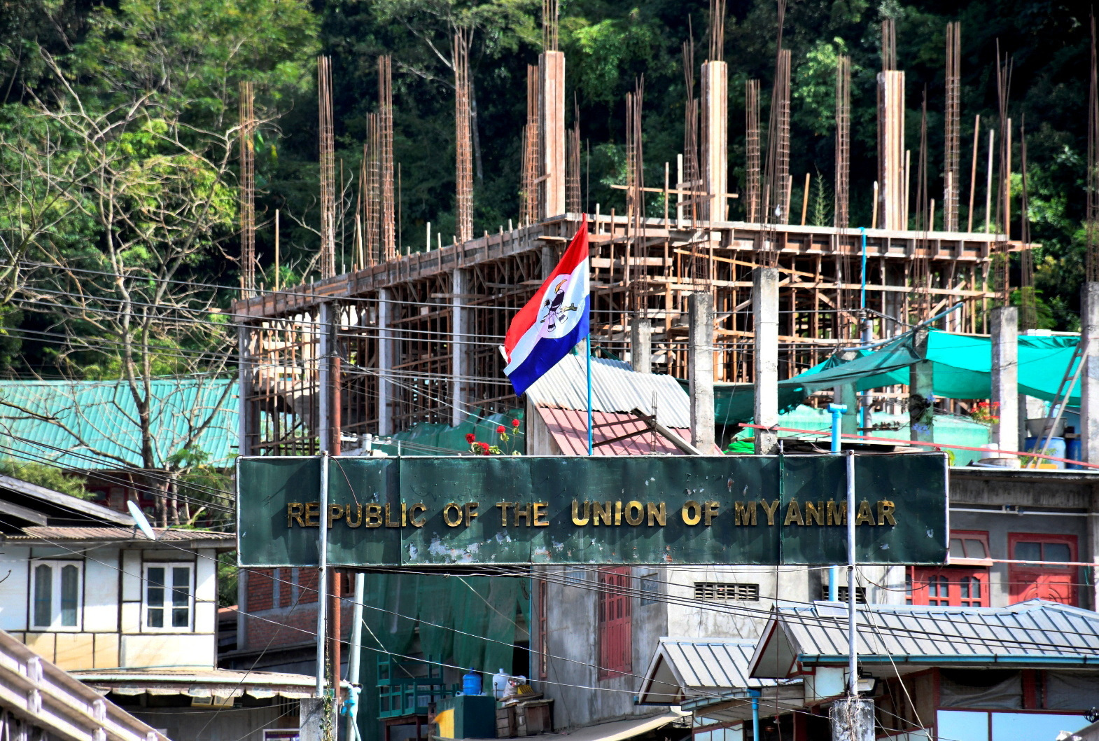 A flag of one of the Myanmar rebel forces is installed next to an under-construction structure in Myanmar's Khawmawi village on the India-Myanmar border as seen from Zokhawthar village