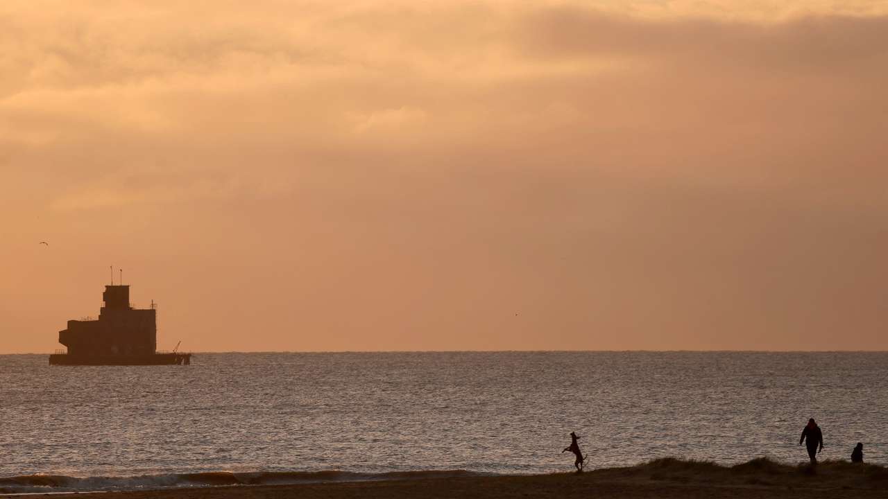 FILE PHOTO: People visit the beach, near the location where a tanker carrying jet fuel for the U.S. military was hit by a container ship, off the coast of Cleethorpes
