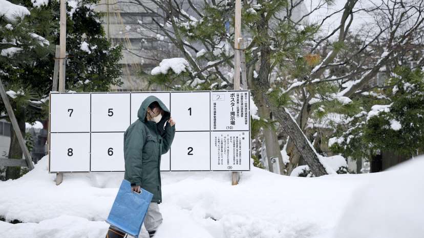 A person walks past a bulletin board for posters of candidates for the February 8 snap election, where snow has accumulated, in Fukui