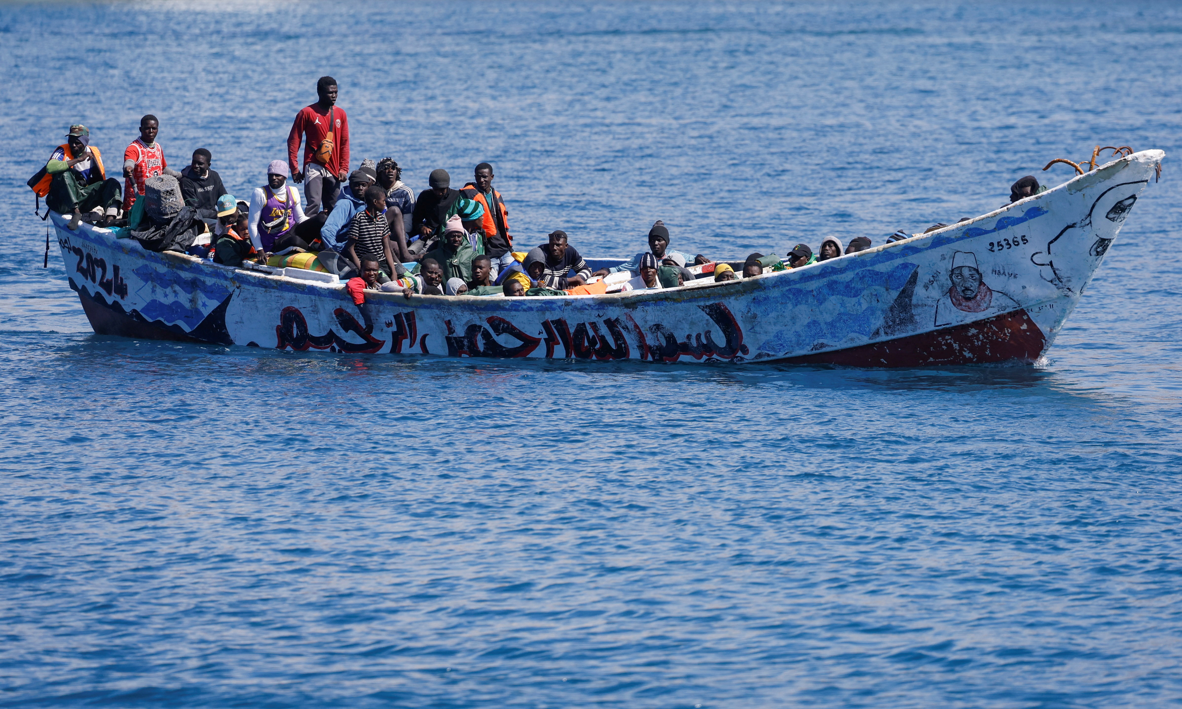Migrants wait to disembark from a fiber boat in the port of Arguineguin