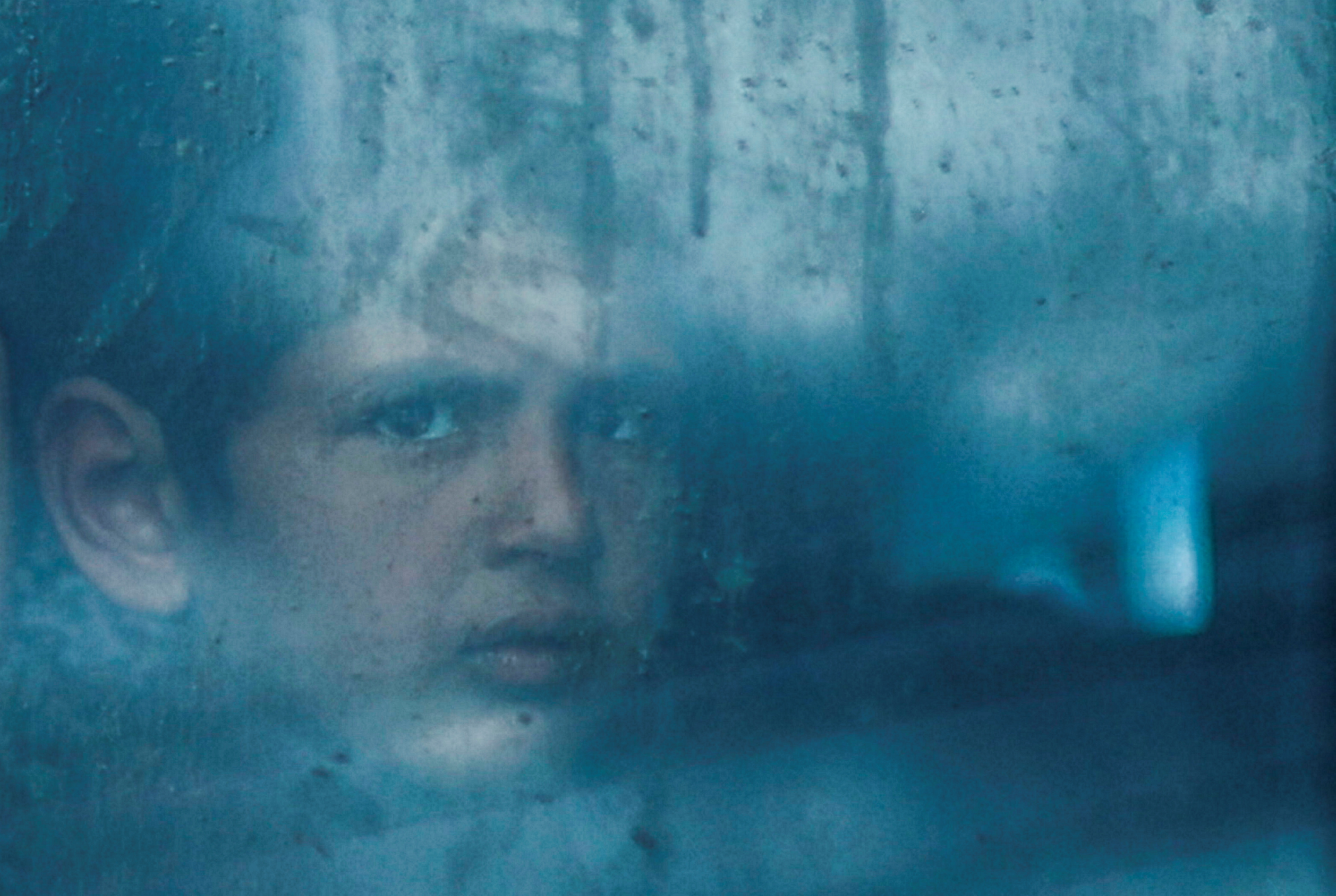 A displaced Palestinian looks out from a bus window, in Rafah