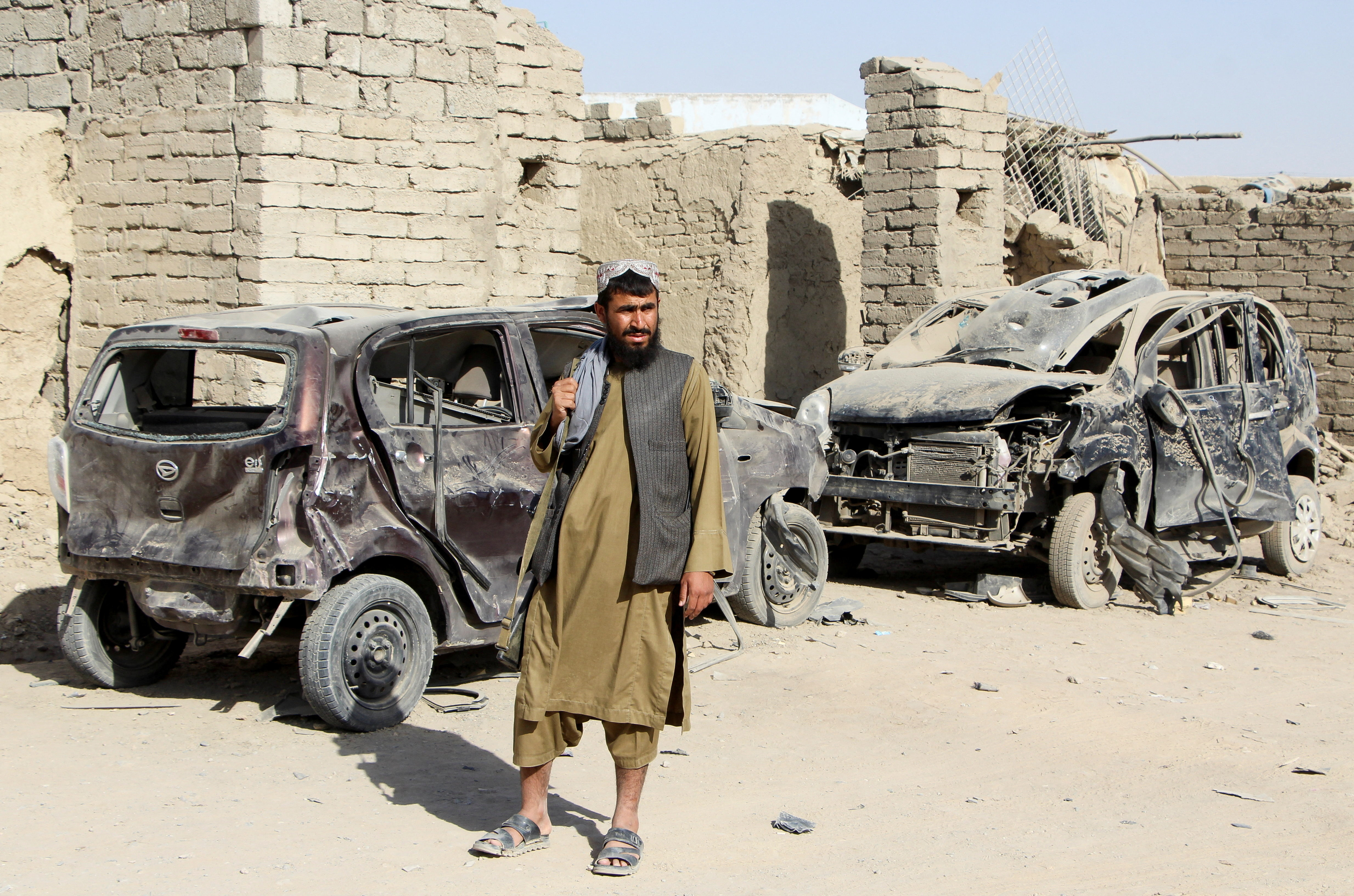 A Taliban fighter stands next to vehicles destroyed during an airstrike following a temporary ceasefire amid the conflict between Afghanistan and Pakistan, in Spin Boldak