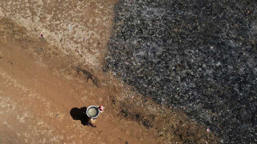 FILE PHOTO: A drone view of a woman carrying a utensil filled with water after drawing it from a well on a hot day in Kasara