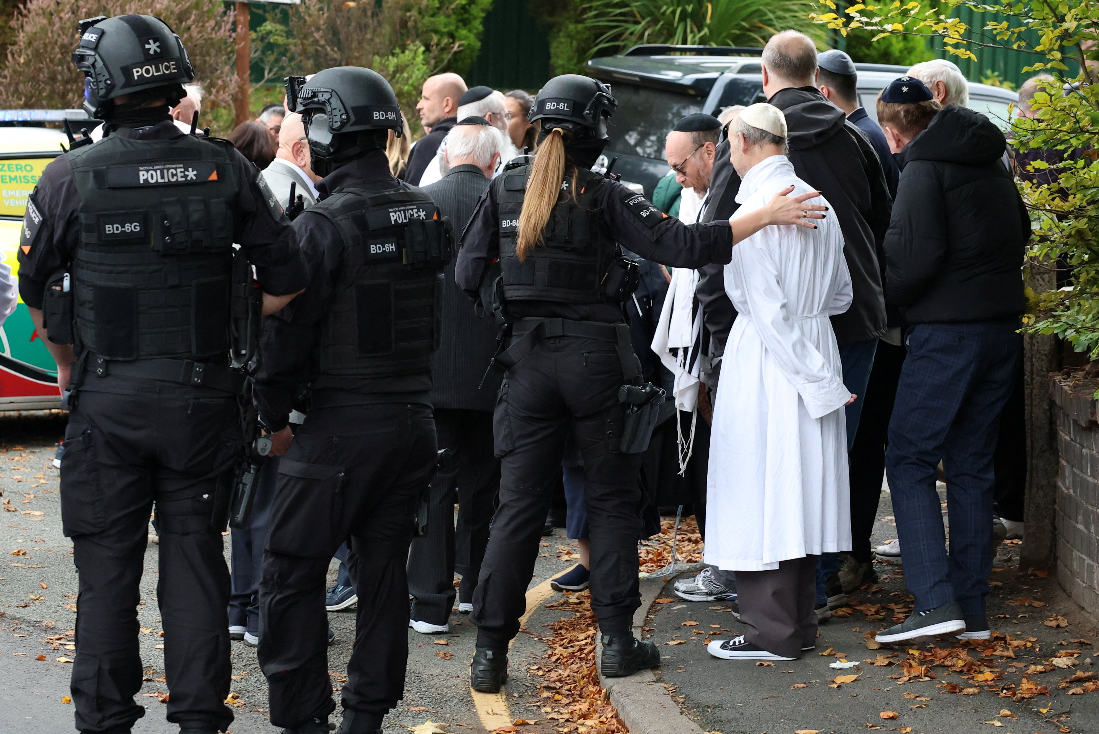 People gather near the scene following an incident outside a synagogue, in Manchester