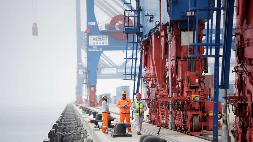 FILE PHOTO: Workers stand next to cranes at the new megaport being built by China's state-owned Cosco Shipping, in Chancay