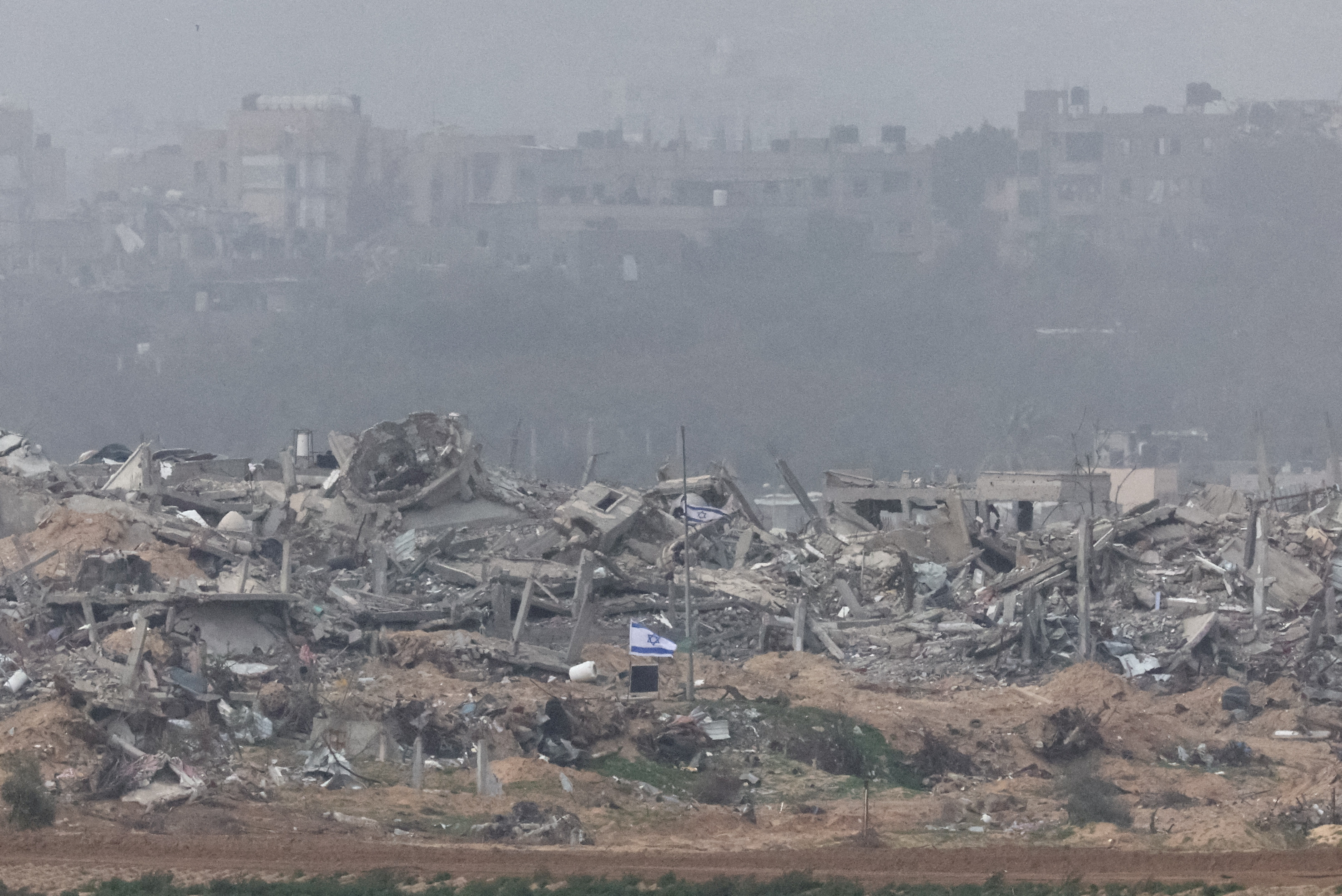 Israeli flags fly next to the rubble of destroyed buildings in Gaza, as seen from southern Israel