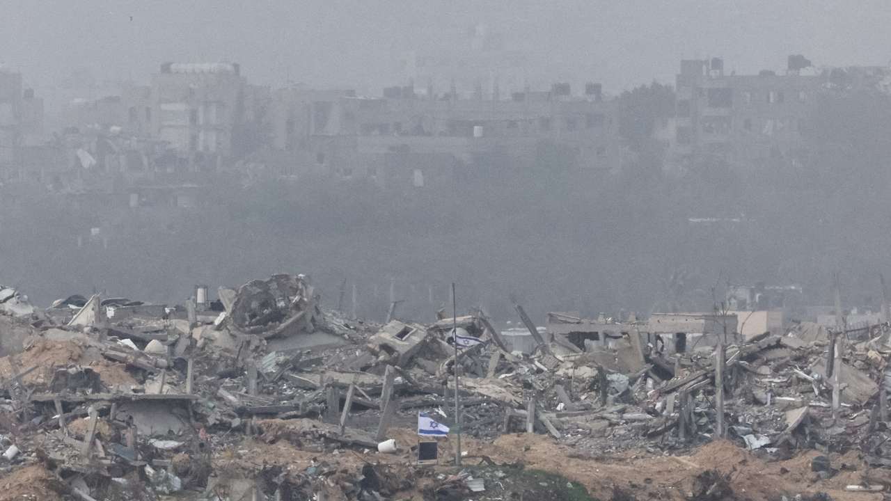 Israeli flags fly next to the rubble of destroyed buildings in Gaza, as seen from southern Israel
