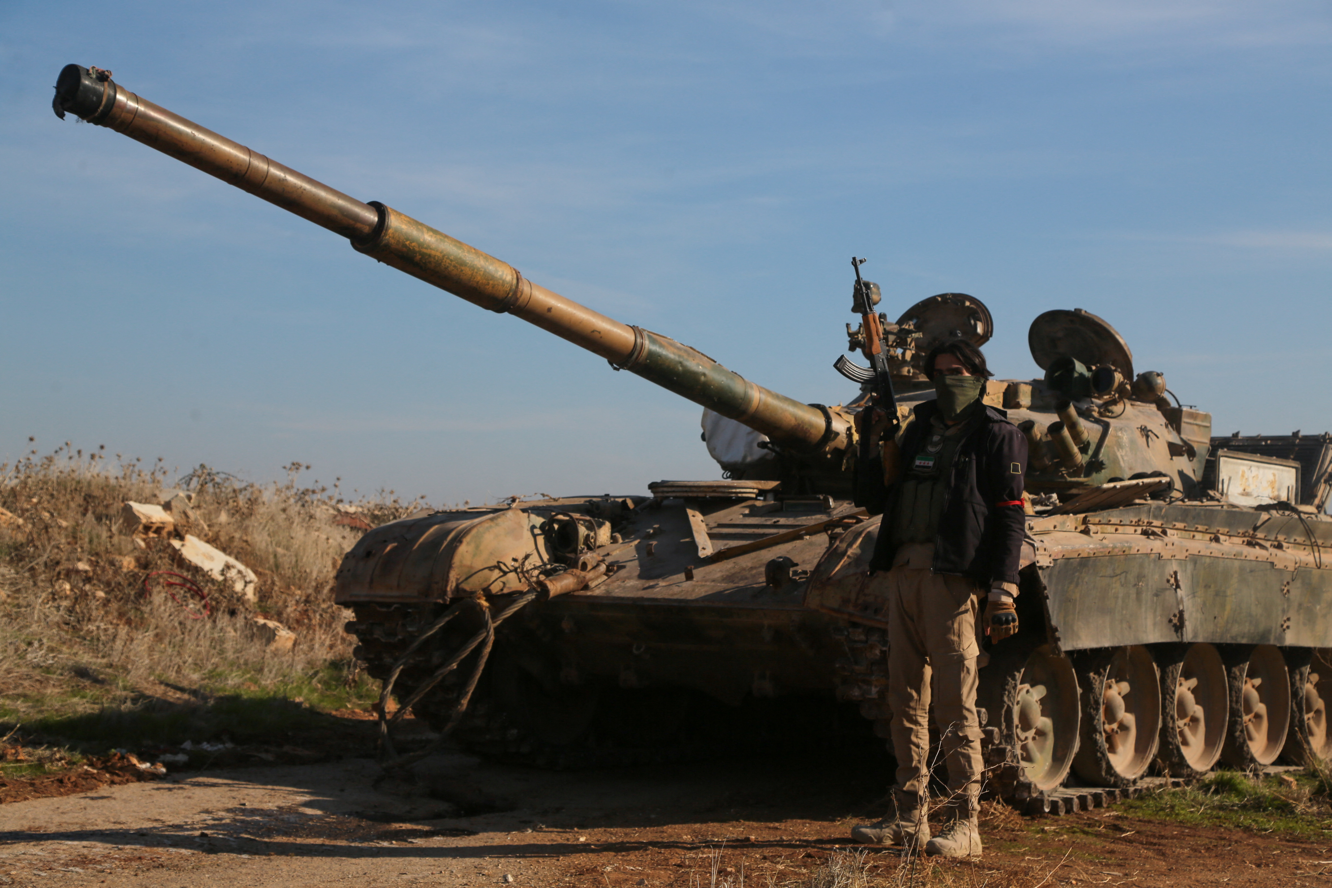 A rebel fighter holds his weapon as he stands in front of a military vehicle in Menagh