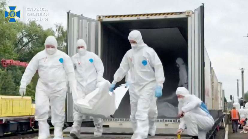 People in hazmat suits carry what is said to be remains of Ukrainian soldiers received from Russia in an unknown location